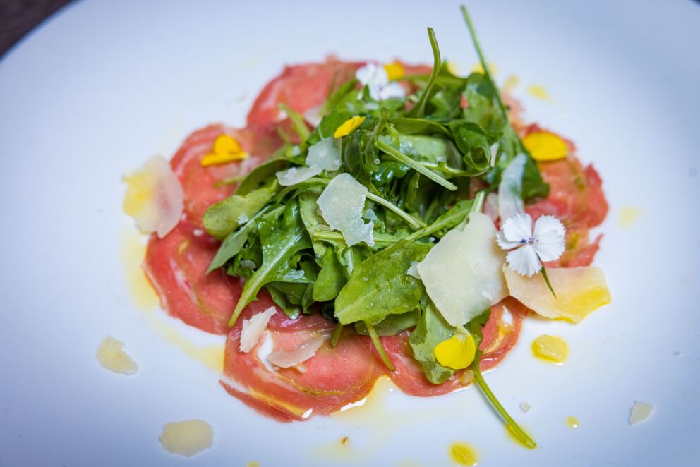 Kalb Carpaccio mit frischen Salatblättern und geriebenen Käse