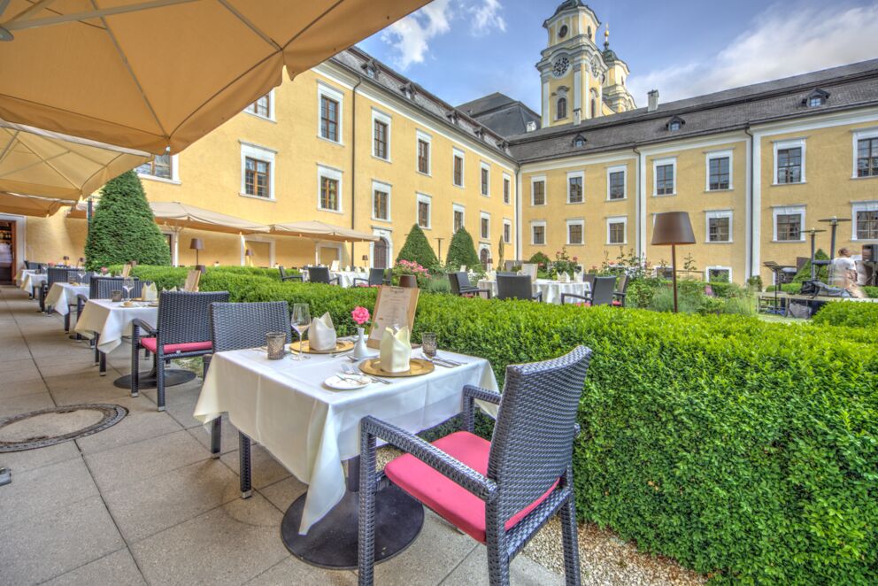 Im Schlossgarten des Schlosshotels Mondsee stehen viele Tische.